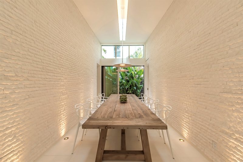 The dining room features walls clad in split-face Bianco Luna limestone. Photography: Tim Singer & Associates, Coldwell Banker Florida.
